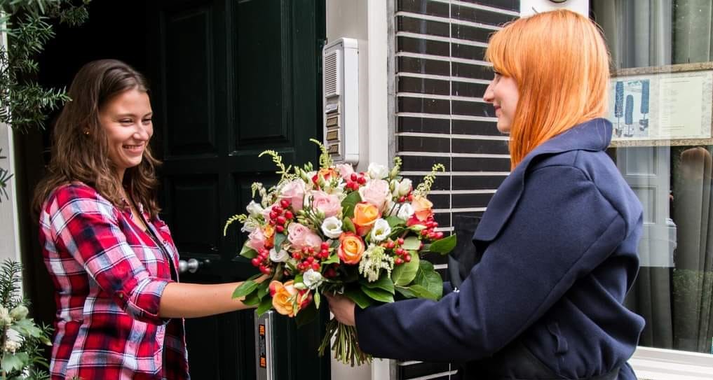 Vrouw geeft boeket bloemen af op huisadres